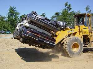 photo of a front end loader lifting a crushed car